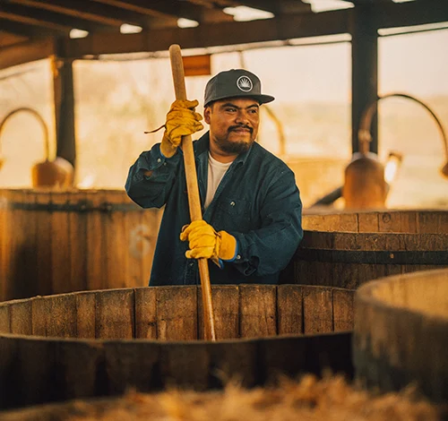 Worker stirring agave mash