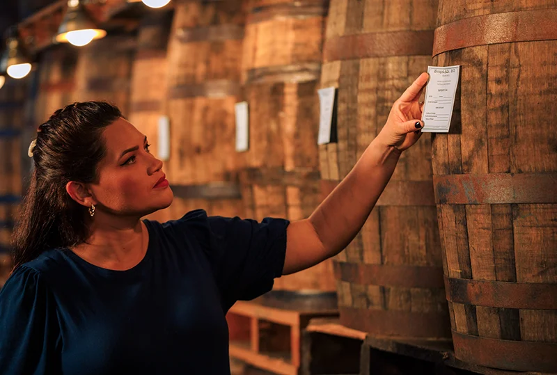 Person inspecting a barrel of whisky